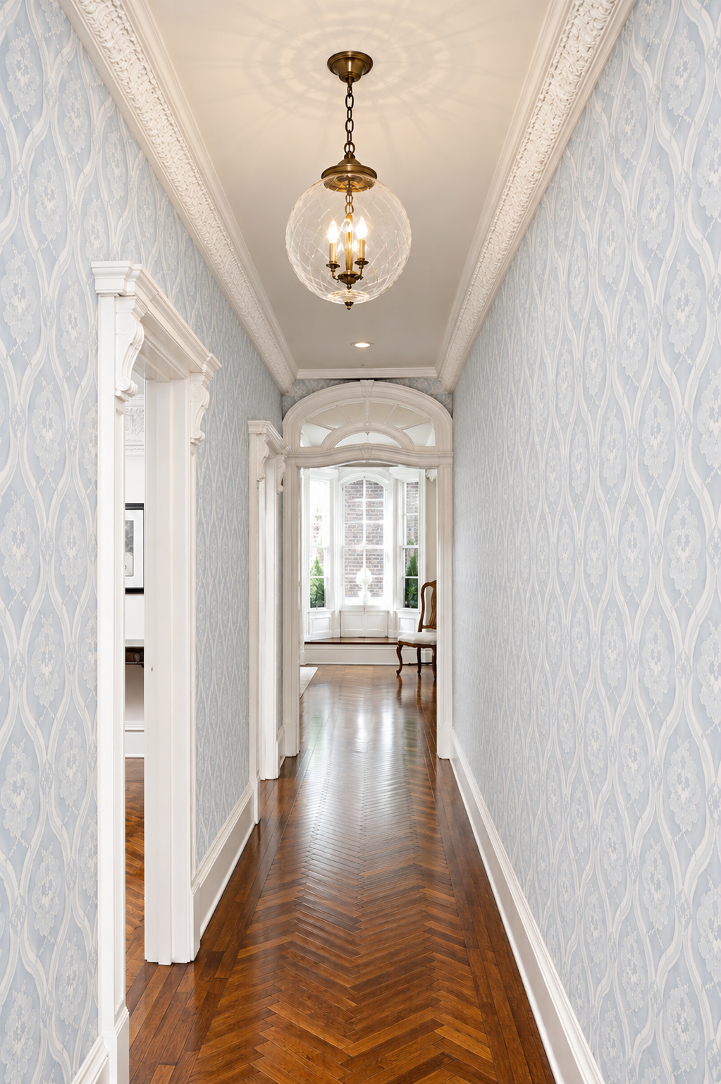 Elegant hallway with damask wallpaper, ornate molding, and crystal pendant