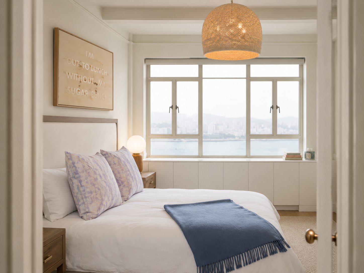 Serene bedroom with rattan pendant, harbor view, and lavender tie-dye pillows