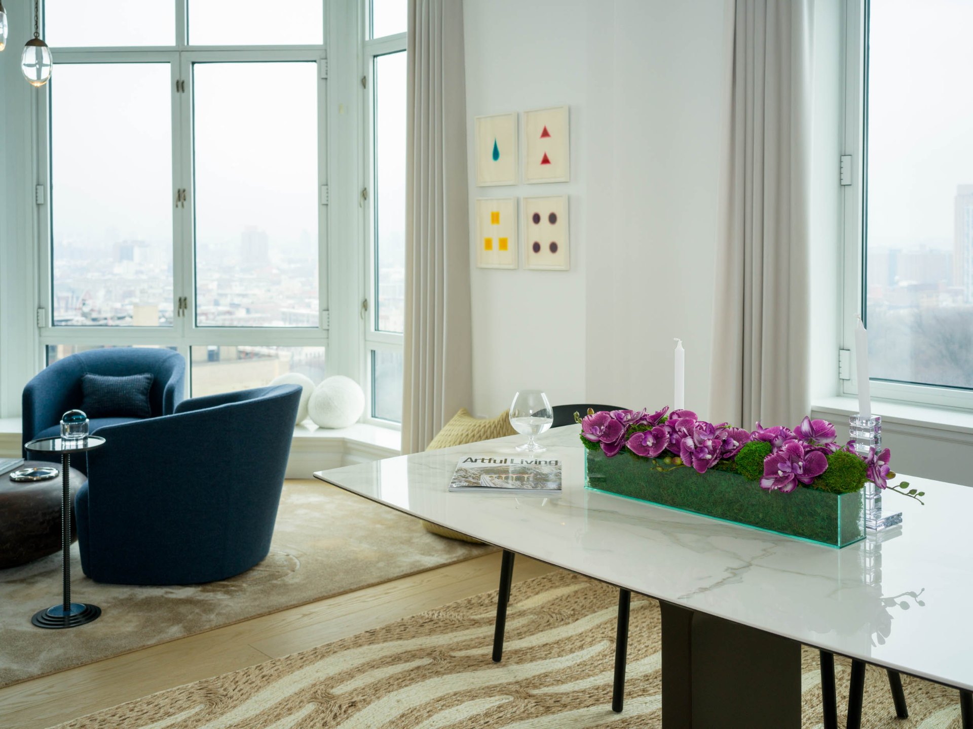 Bright living and dining area with navy chairs, city view, and orchid centerpiece